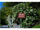 Schild im italienischen Dialekt, geschmückt mit reichlich Blumen.
